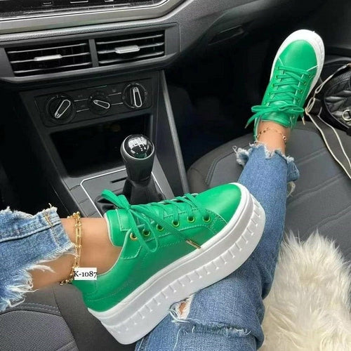 A pair of white casual platform sneakers worn by a person sitting in a car, with the car's interior and the person's jeans visible.