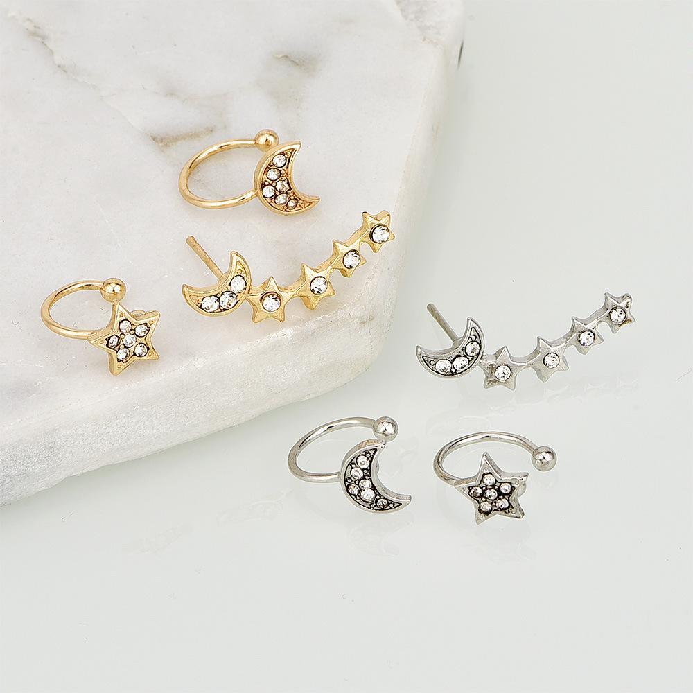 Set of gold and silver hoop earrings with star and moon designs on a marble surface.