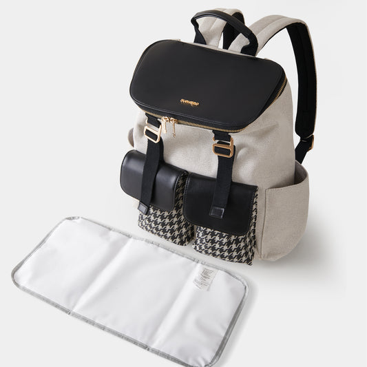 Backpack with black top section and houndstooth pattern, accompanied by a white changing pad on a light gray background.