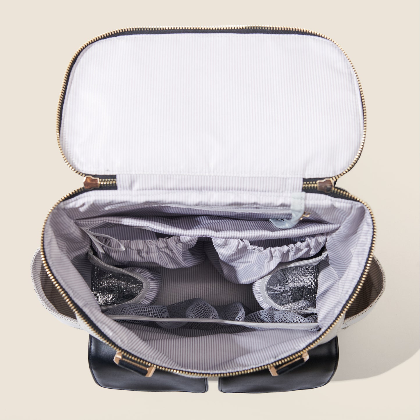 Open black travel bag with white interior on a beige background