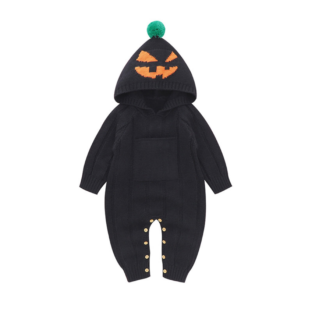 Black baby onesie with pumpkin face design and green pom-pom hat on white background