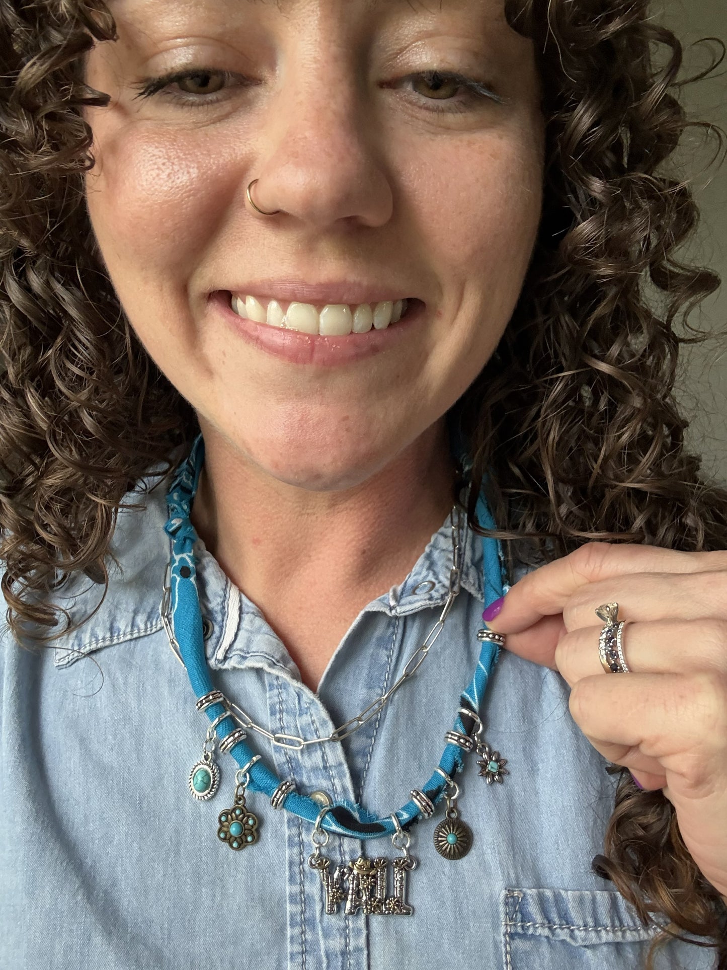 Woman wearing a blue necklace with charms, smiling at the camera.