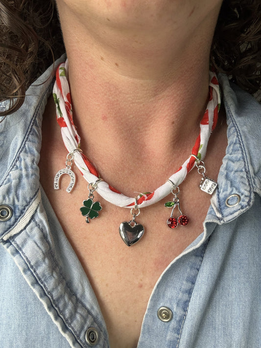 Necklace with various charms worn by a person in a denim jacket.
