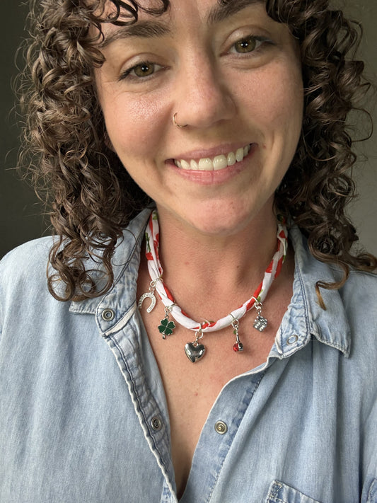 Woman wearing a denim shirt and a necklace with various pendants against a neutral background