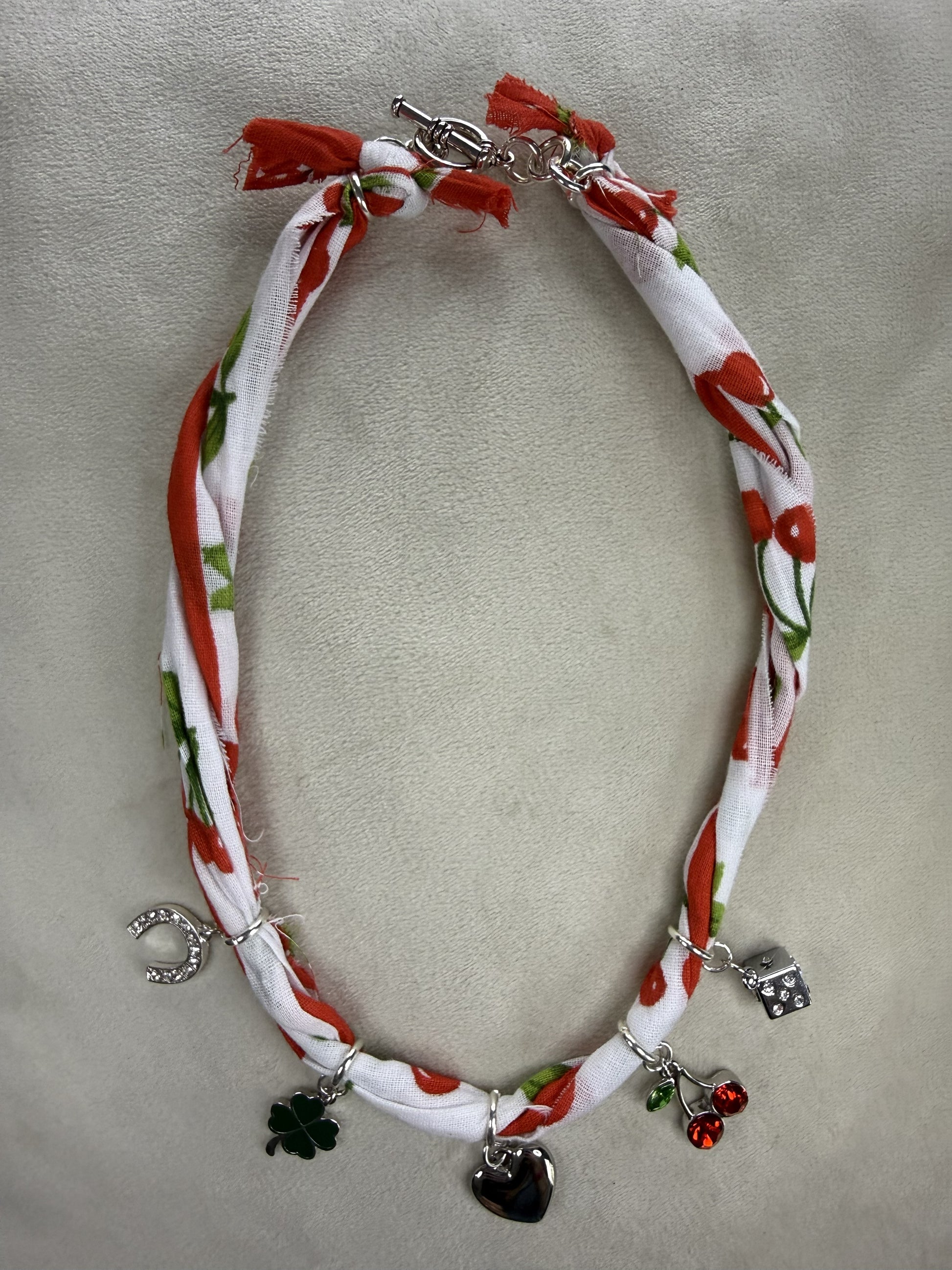 Necklace with floral pattern and charms on a light gray background