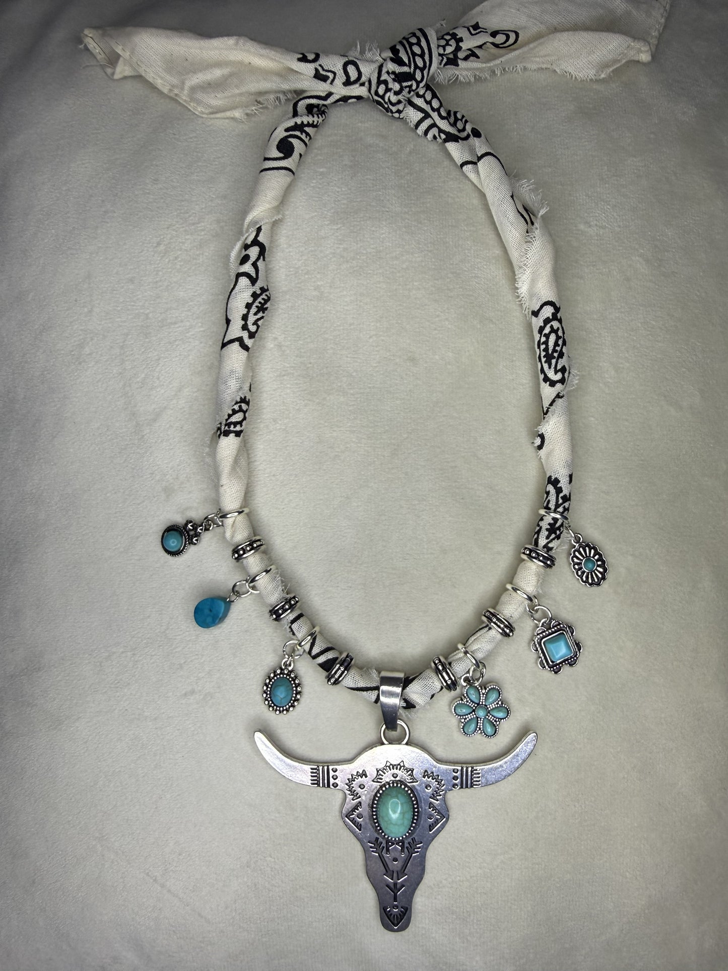 Necklace with bull head pendant and turquoise stones on a light gray background