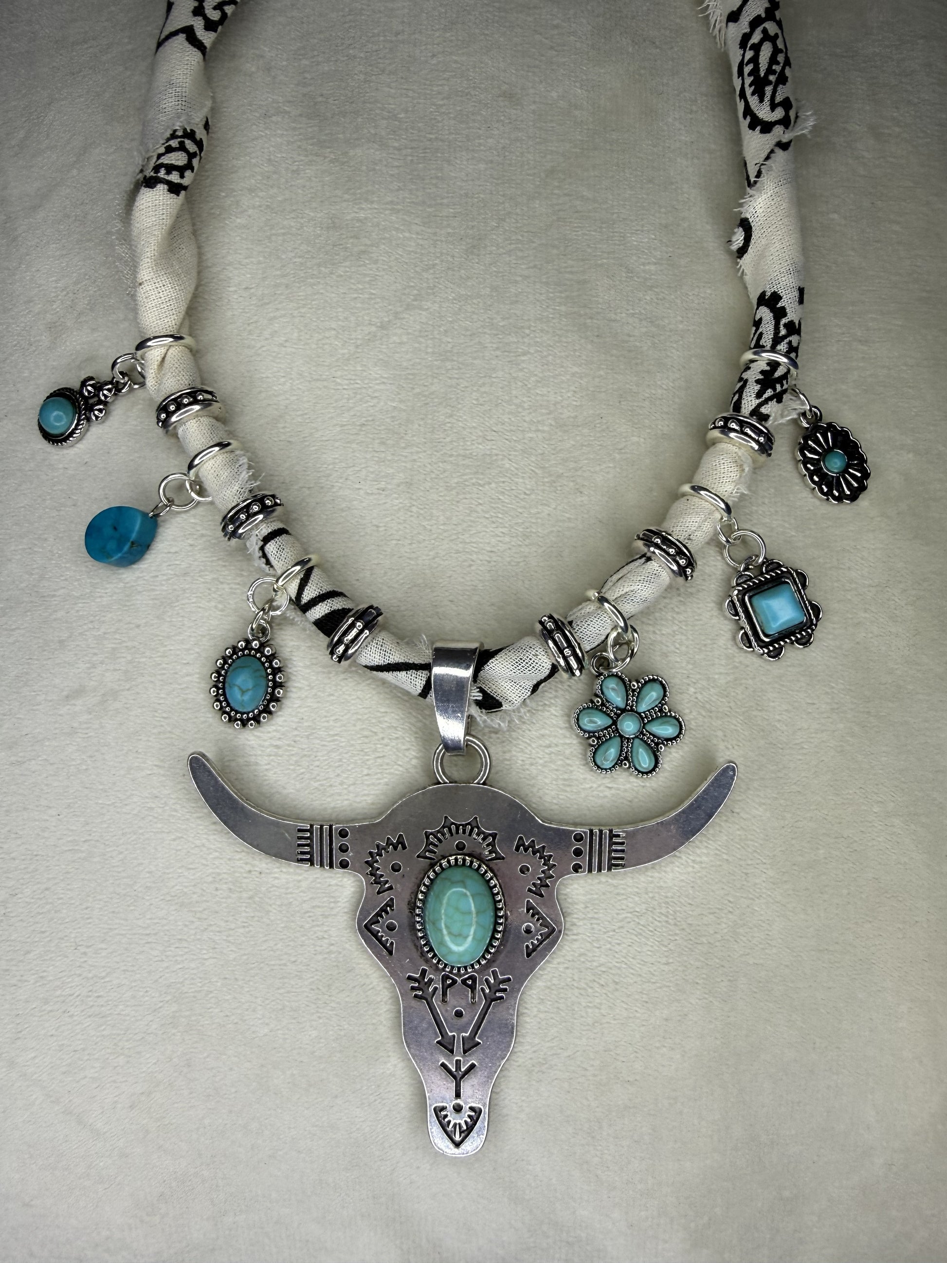 Necklace with longhorn bull skull pendant and turquoise stones on a gray background