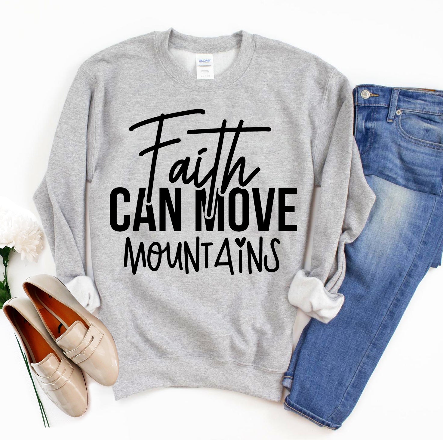 Gray sweatshirt with 'Faith Can Move Mountains' text, paired with jeans and shoes on a white background