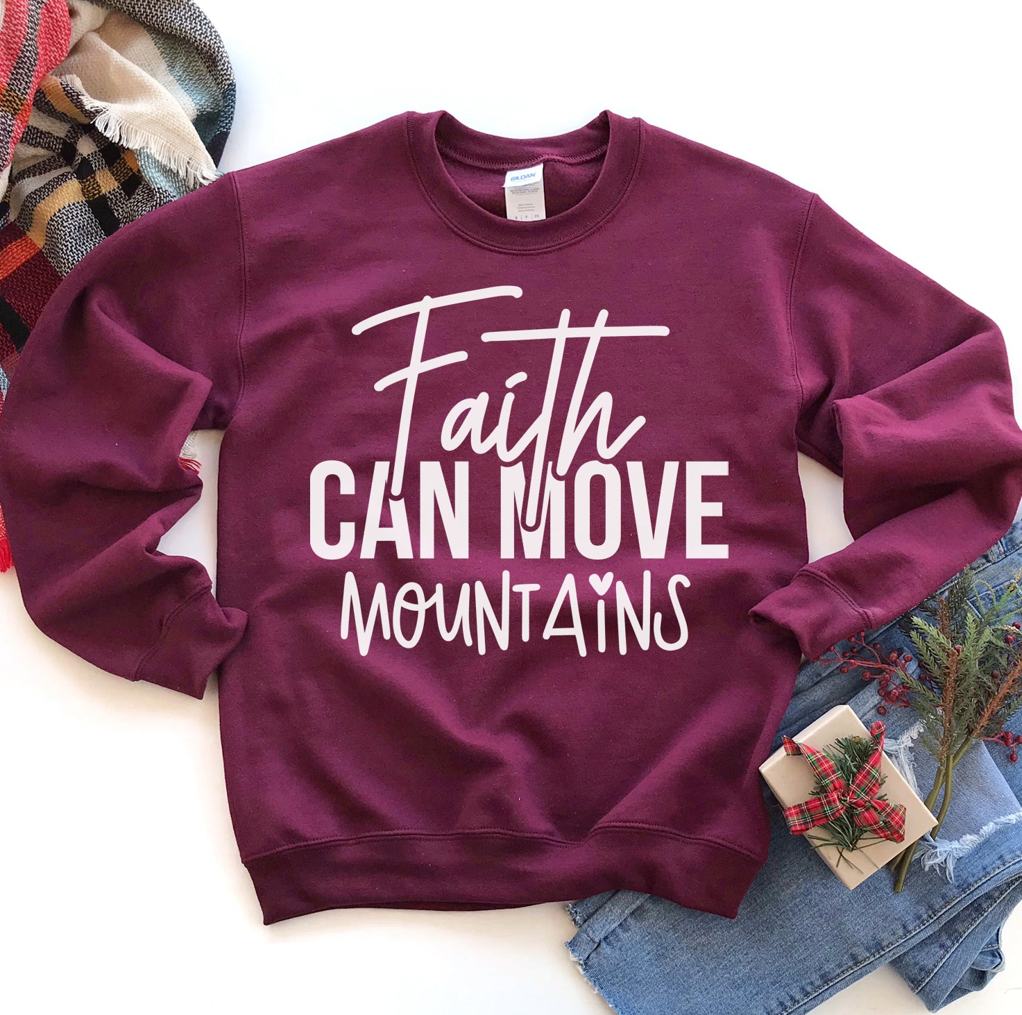Maroon sweatshirt with 'Faith Can Move Mountains' text on a white background