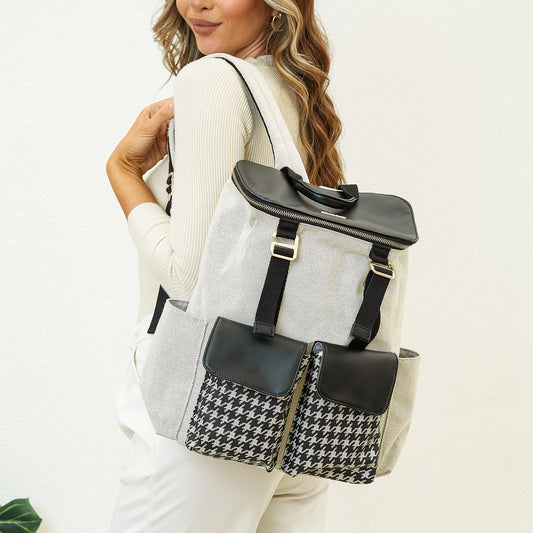 Woman carrying a gray backpack with black accents and a houndstooth pattern pocket.
